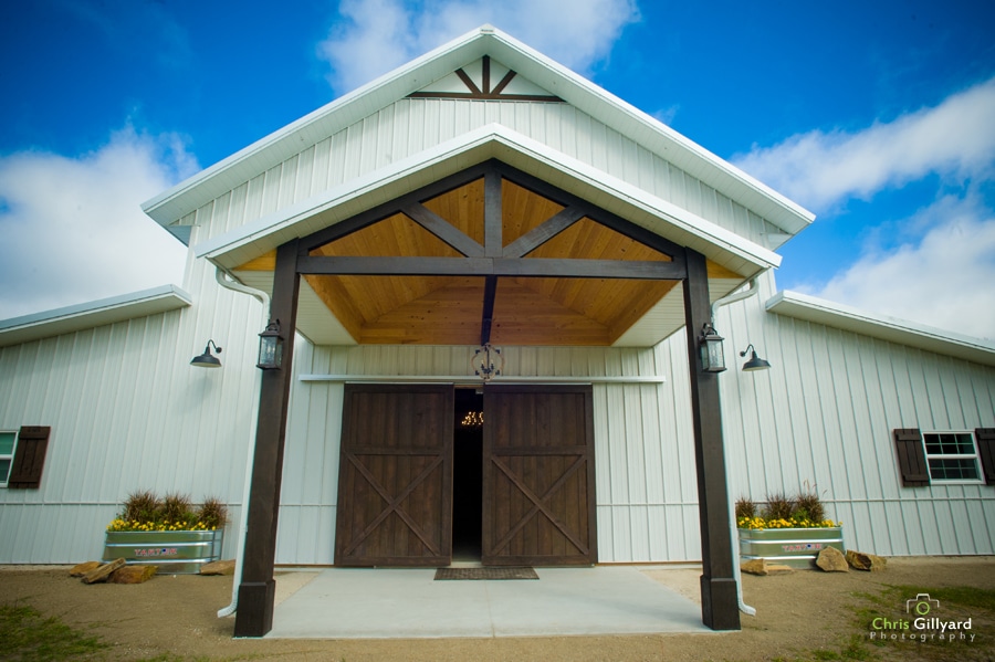 entrance to large white barn with brown doors at legacy at oak meadows wedding venue